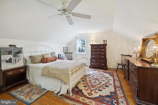 bedroom with ceiling fan with notable chandelier, vaulted ceiling, and hardwood / wood-style flooring