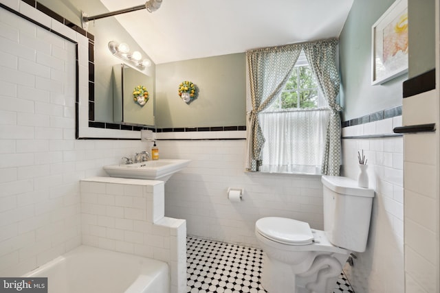 bathroom featuring tile walls, vaulted ceiling, sink, and toilet