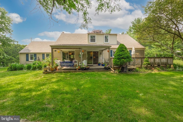 rear view of house featuring a lawn and a deck