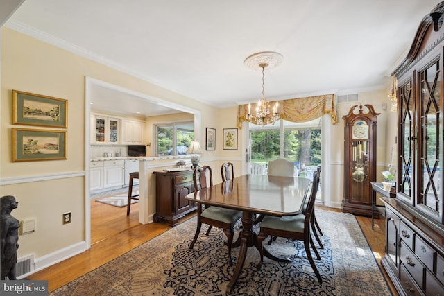 dining room featuring light hardwood / wood-style flooring, a chandelier, and ornamental molding