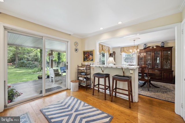 kitchen featuring a breakfast bar, light wood-type flooring, hanging light fixtures, an inviting chandelier, and ornamental molding