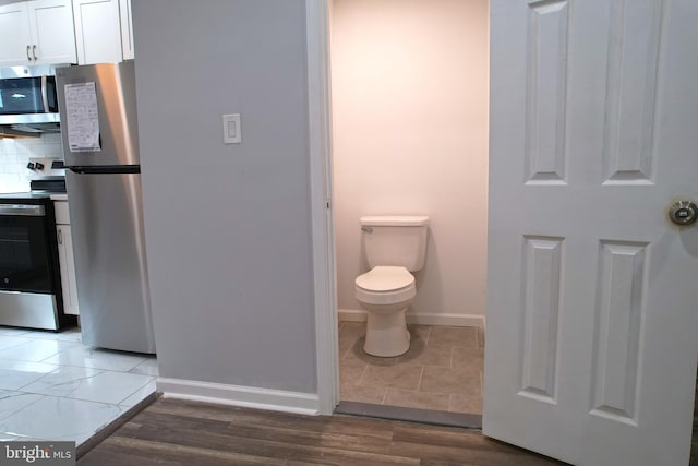 bathroom featuring tasteful backsplash, toilet, and hardwood / wood-style flooring