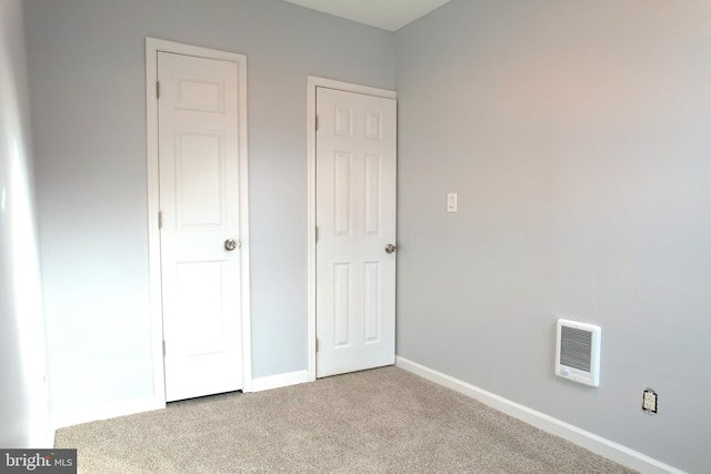 unfurnished bedroom with heating unit and light colored carpet