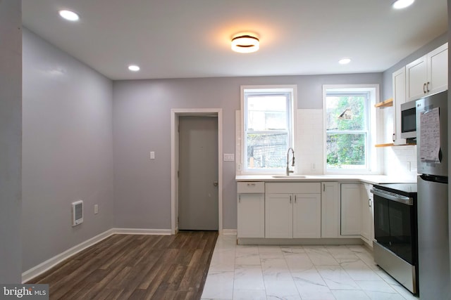 kitchen featuring light hardwood / wood-style floors, sink, white cabinets, stainless steel appliances, and backsplash