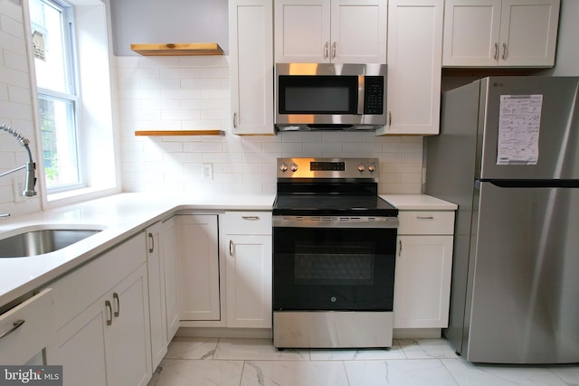 kitchen with decorative backsplash, white cabinetry, sink, and stainless steel appliances