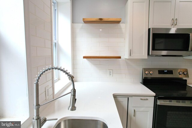 kitchen featuring white cabinetry, appliances with stainless steel finishes, sink, and backsplash