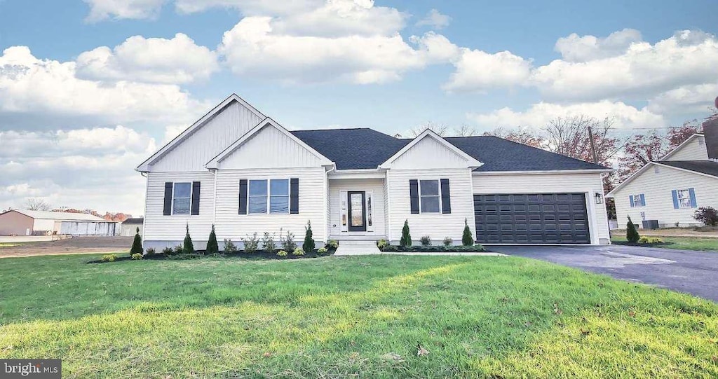 view of front of house featuring central air condition unit, a front yard, and a garage