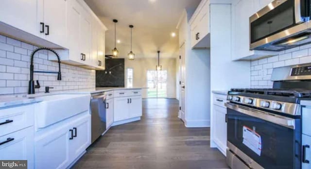 kitchen featuring white cabinets, stainless steel appliances, hanging light fixtures, and decorative backsplash