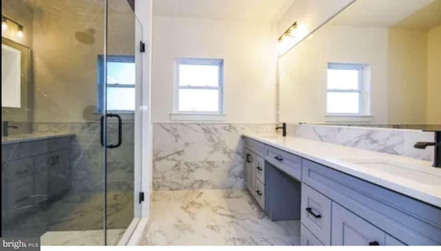 bathroom featuring a healthy amount of sunlight, vanity, tile walls, and an enclosed shower