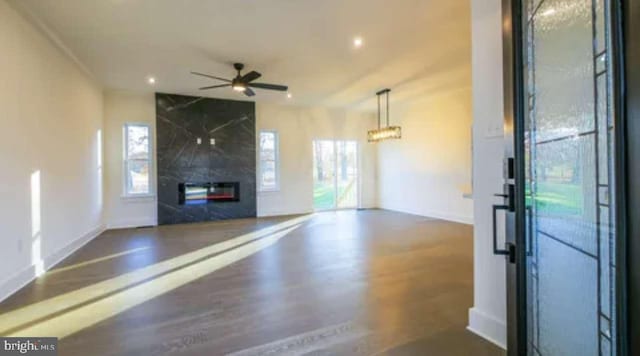 unfurnished living room with ceiling fan with notable chandelier and dark hardwood / wood-style flooring