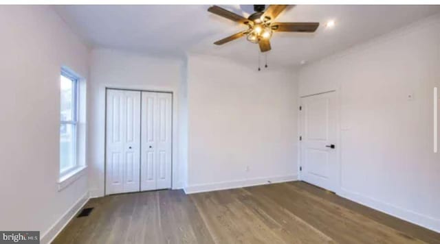 unfurnished bedroom featuring dark wood-type flooring, a closet, and ceiling fan