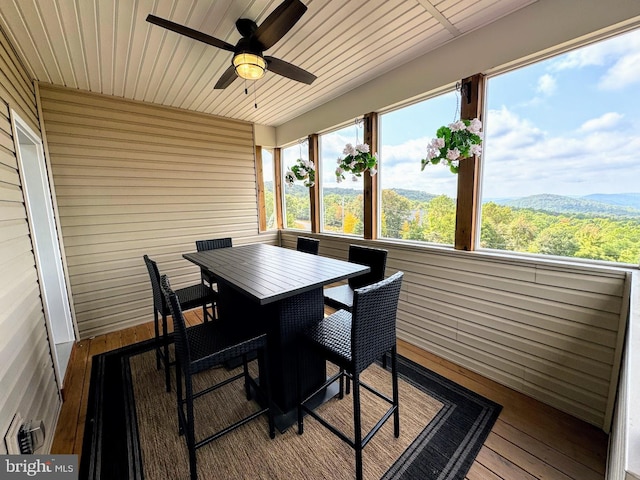 sunroom featuring a mountain view, ceiling fan, and wood ceiling