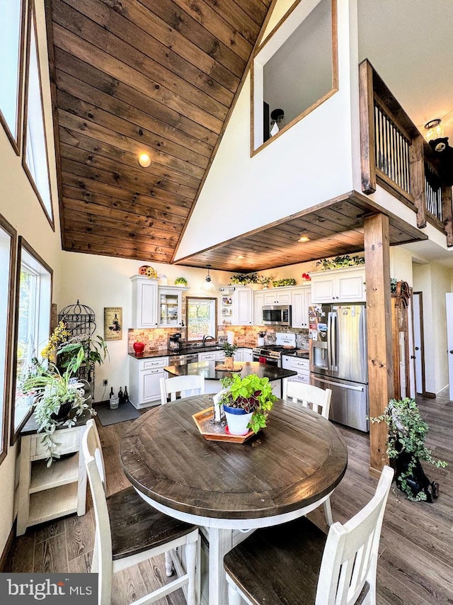 dining space with dark hardwood / wood-style flooring, high vaulted ceiling, and wooden ceiling