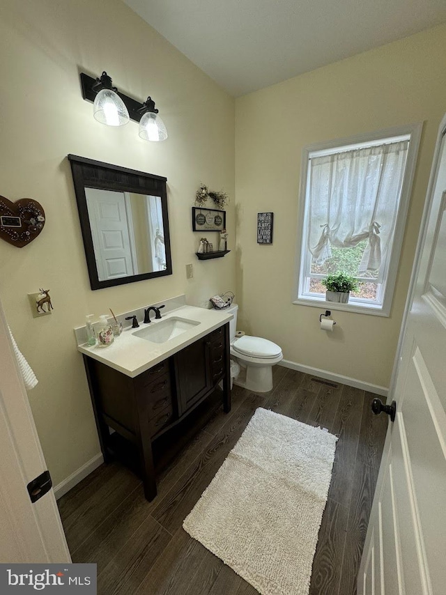 bathroom featuring toilet, vanity, and hardwood / wood-style flooring