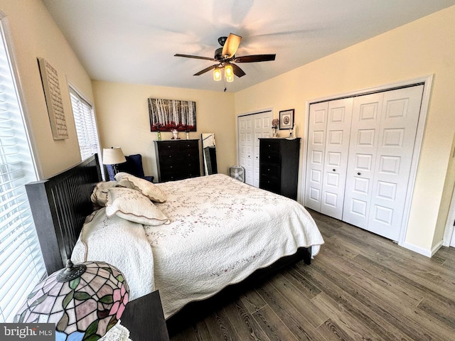 bedroom with ceiling fan, dark wood-type flooring, and multiple closets