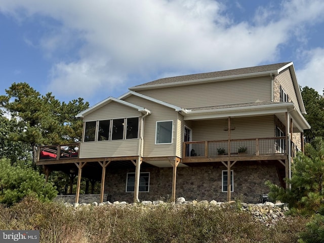 rear view of property featuring a wooden deck and a sunroom