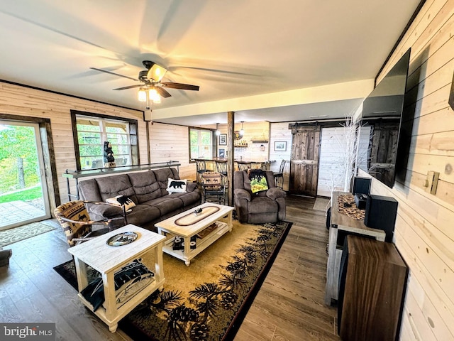 living room featuring hardwood / wood-style floors, ceiling fan, a barn door, and wooden walls