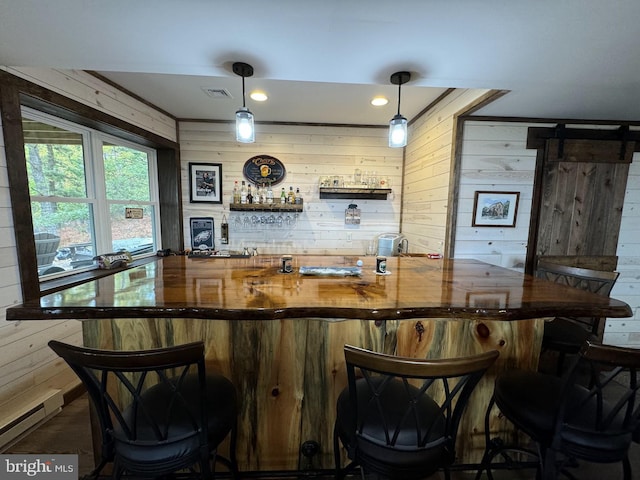 bar featuring a barn door, wood walls, and decorative light fixtures