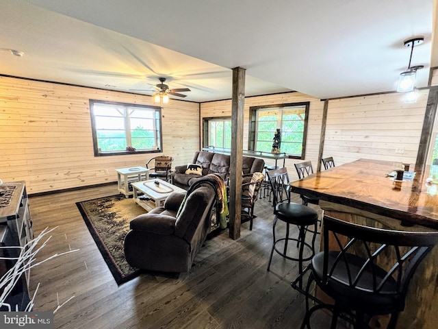 living room with ceiling fan, wood walls, dark hardwood / wood-style flooring, and a wealth of natural light