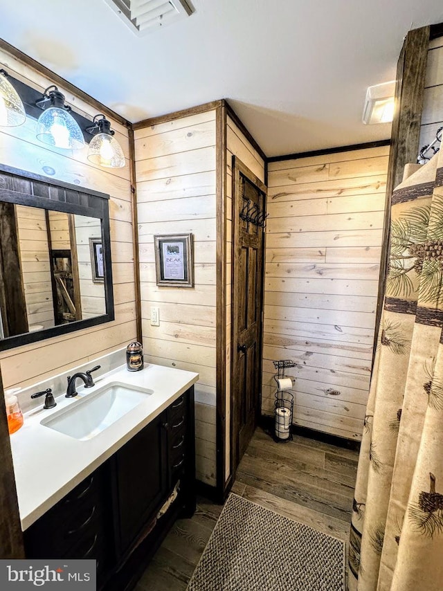 bathroom with wood-type flooring, vanity, and wood walls