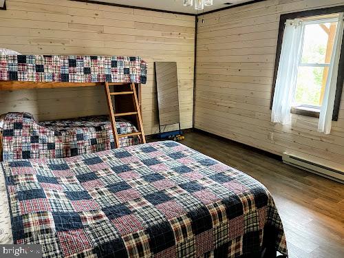 bedroom with dark wood-type flooring and wood walls