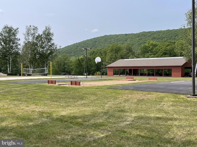 view of community with volleyball court, a mountain view, and a lawn