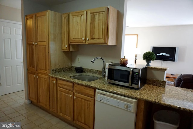 kitchen featuring light stone countertops, sink, white dishwasher, and light tile patterned floors