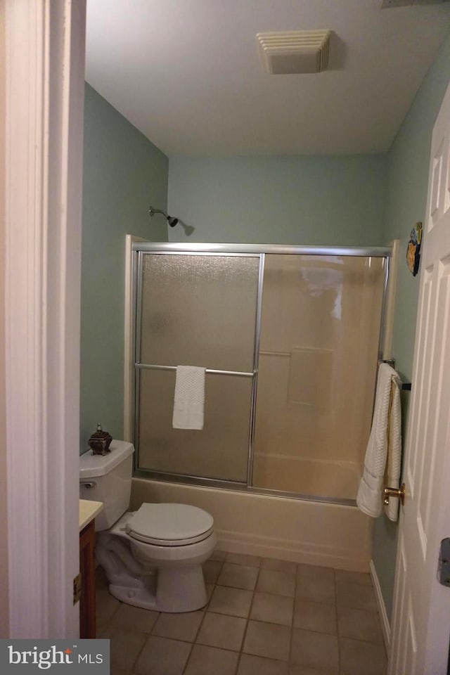 full bathroom featuring toilet, vanity, tile patterned floors, and bath / shower combo with glass door