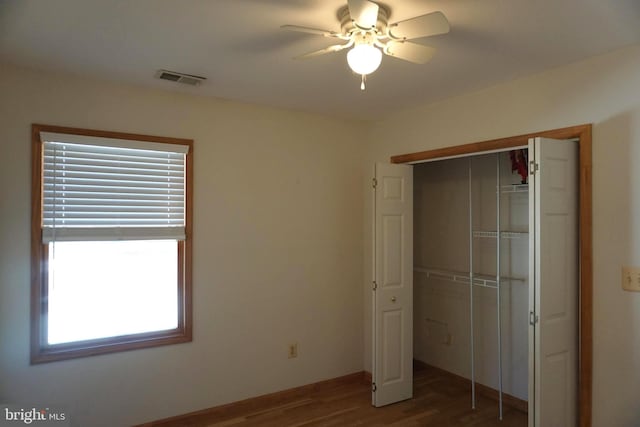 unfurnished bedroom featuring multiple windows, ceiling fan, a closet, and hardwood / wood-style flooring