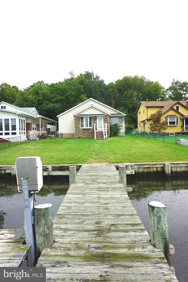 view of dock with a lawn and a water view