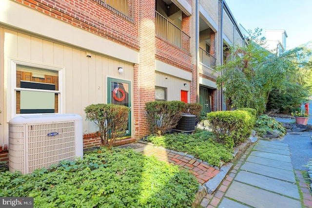 exterior space with cooling unit and brick siding