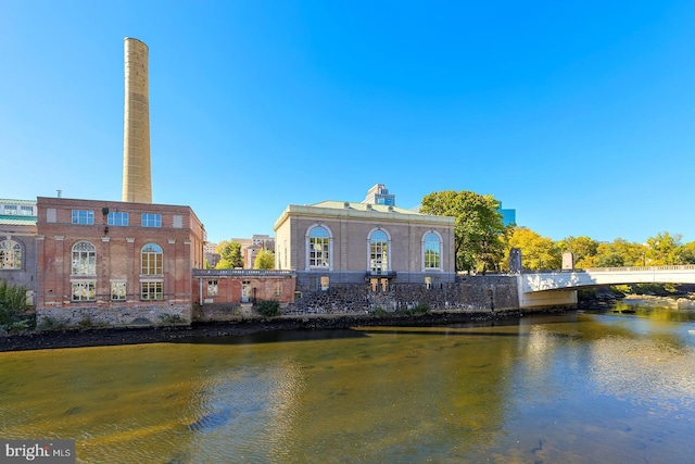 rear view of house featuring a chimney, brick siding, and a water view