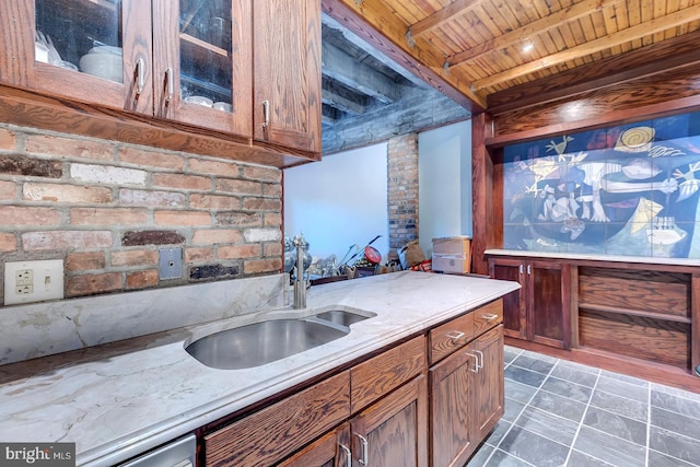 kitchen with glass insert cabinets, wooden ceiling, light stone counters, a sink, and brown cabinets