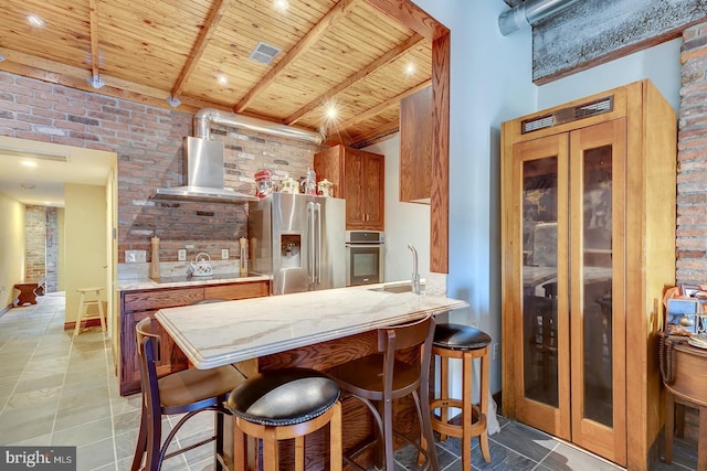 kitchen with a sink, wall chimney range hood, wood ceiling, beam ceiling, and stainless steel appliances