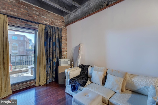 living area featuring brick wall and dark wood finished floors