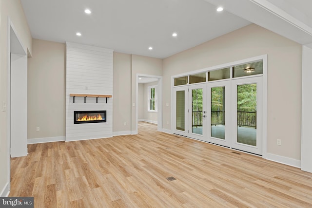 unfurnished living room featuring light hardwood / wood-style floors and a large fireplace