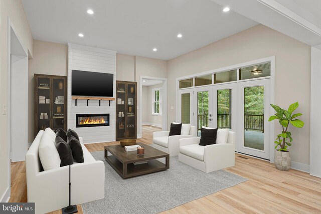 living room with french doors, a large fireplace, and light wood-type flooring