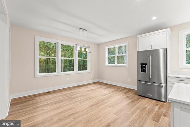 kitchen featuring high end fridge, white cabinetry, a healthy amount of sunlight, and light wood-type flooring