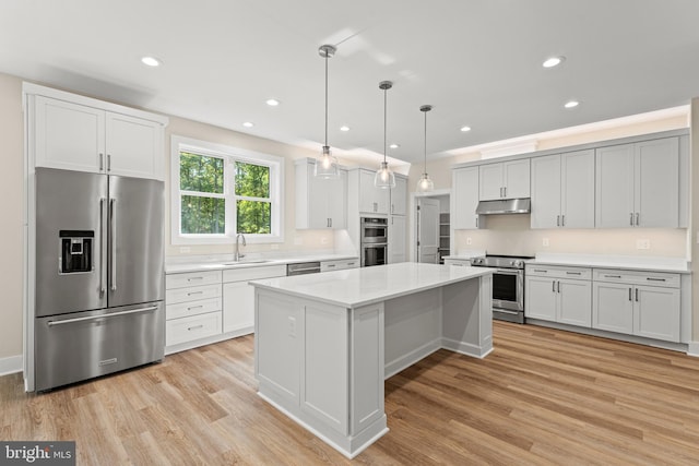 kitchen with a kitchen island, light hardwood / wood-style flooring, stainless steel appliances, sink, and pendant lighting