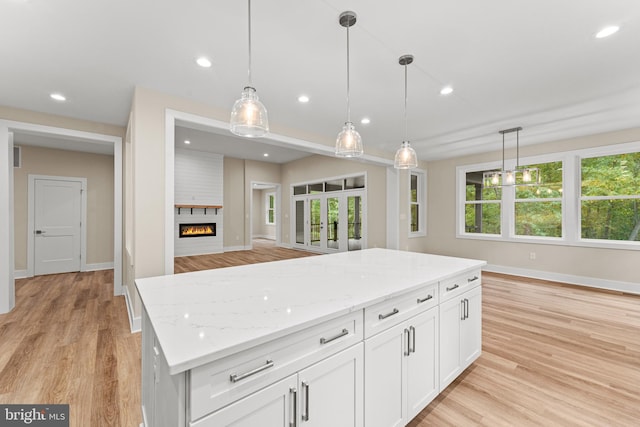 kitchen with pendant lighting, plenty of natural light, a fireplace, and white cabinets