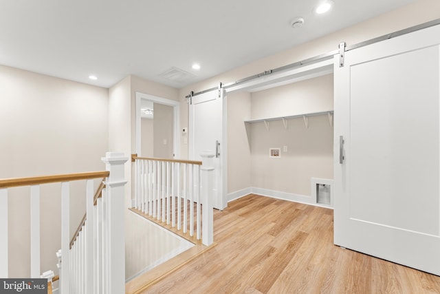 laundry room with light hardwood / wood-style flooring, hookup for a washing machine, and a barn door