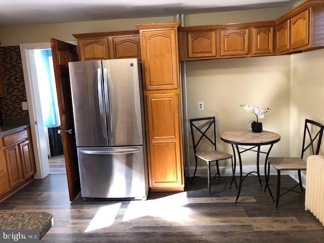 kitchen with stainless steel refrigerator, dark hardwood / wood-style flooring, and radiator heating unit