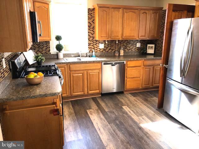 kitchen with dark hardwood / wood-style floors, backsplash, sink, and stainless steel appliances