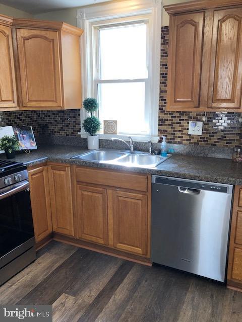 kitchen featuring backsplash, stainless steel appliances, dark wood-type flooring, and sink