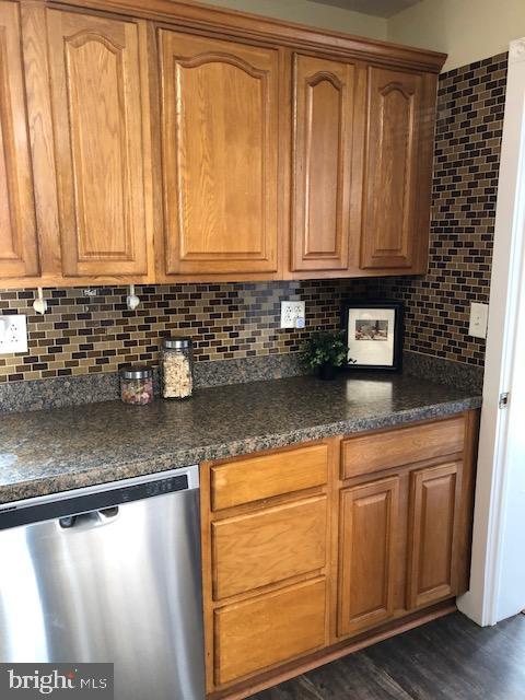 kitchen featuring dark hardwood / wood-style flooring, decorative backsplash, and stainless steel dishwasher