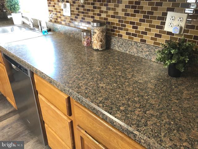 room details with decorative backsplash, dishwasher, and sink