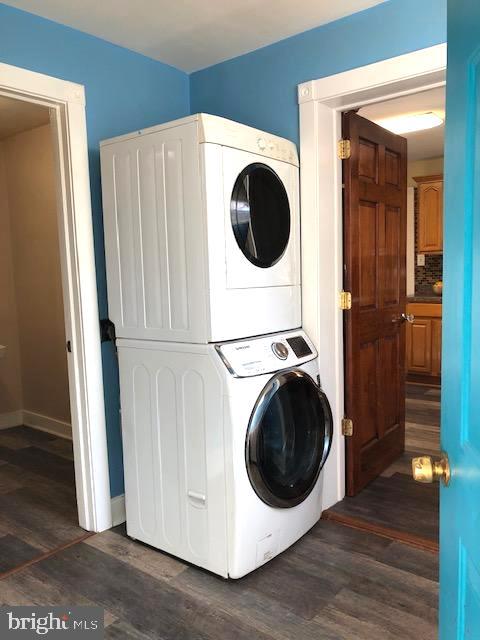 washroom with stacked washer and clothes dryer and dark hardwood / wood-style flooring