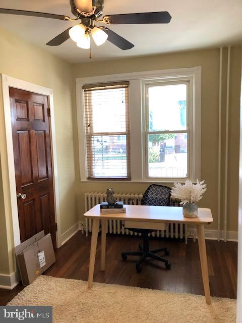 office with radiator heating unit, ceiling fan, and dark wood-type flooring