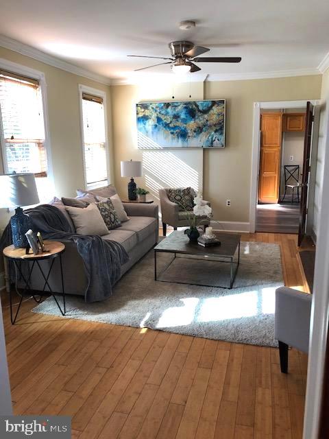 living room with ceiling fan, hardwood / wood-style flooring, and crown molding