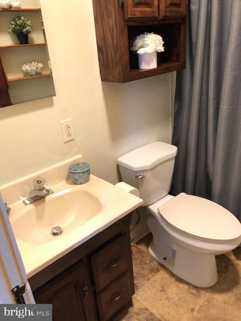 bathroom featuring curtained shower, vanity, and toilet